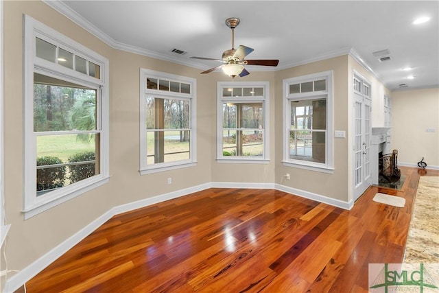 unfurnished dining area featuring visible vents, crown molding, baseboards, and wood finished floors