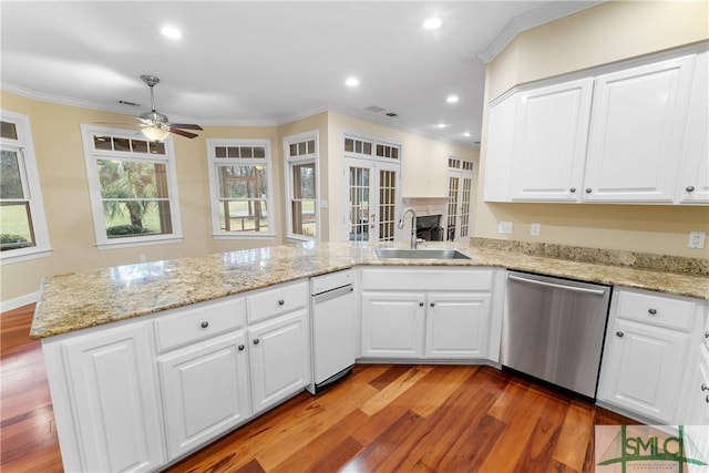 kitchen with light wood finished floors, crown molding, a peninsula, stainless steel dishwasher, and a sink