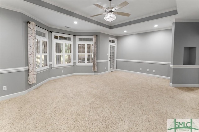 empty room featuring a raised ceiling, recessed lighting, crown molding, and baseboards