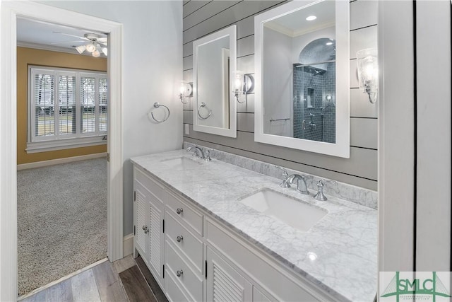 full bathroom with crown molding, double vanity, a tile shower, and a sink