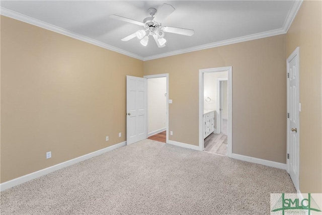 unfurnished bedroom featuring crown molding, baseboards, light colored carpet, ensuite bathroom, and a ceiling fan