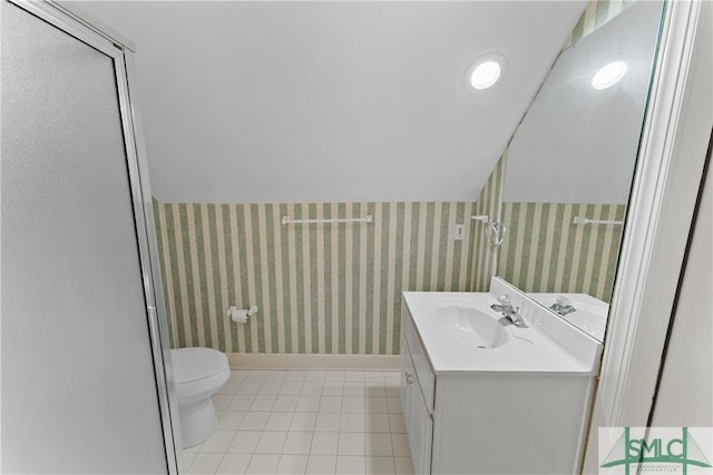 bathroom featuring toilet, wallpapered walls, vanity, and lofted ceiling