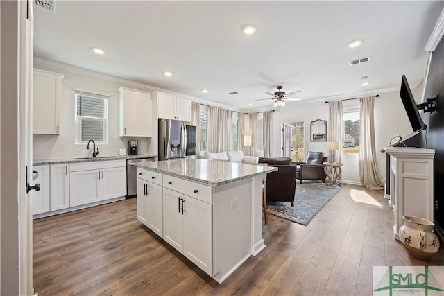 kitchen featuring visible vents, a center island, crown molding, appliances with stainless steel finishes, and dark wood-style flooring