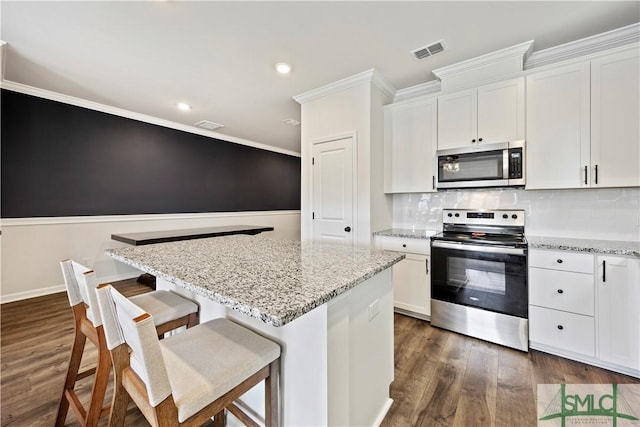 kitchen featuring stainless steel appliances, visible vents, a center island, and white cabinetry