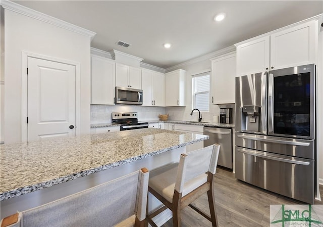 kitchen featuring visible vents, ornamental molding, a sink, white cabinetry, and stainless steel appliances