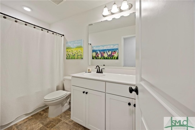 bathroom with stone finish floor, toilet, and vanity