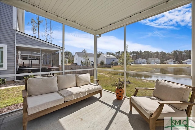 sunroom featuring track lighting, a water view, and a residential view