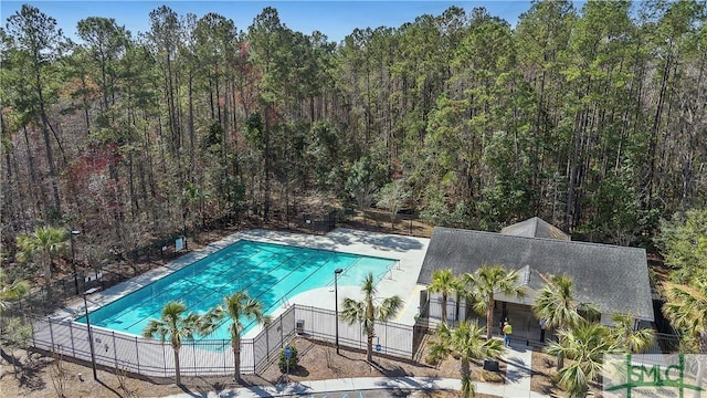 pool featuring a patio area, fence, and a forest view