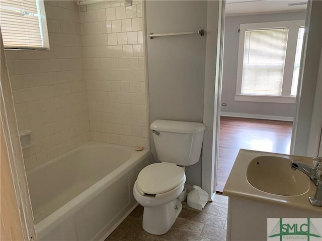 bathroom with shower / bath combination, toilet, vanity, and baseboards