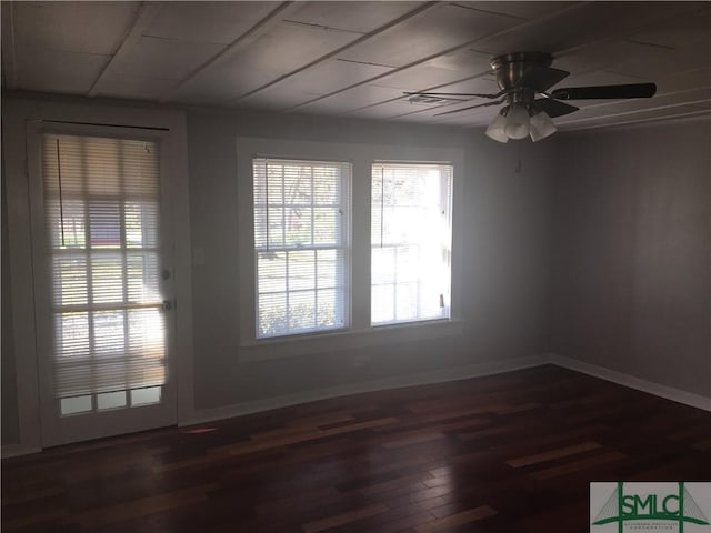 spare room featuring dark wood-type flooring, a ceiling fan, and baseboards