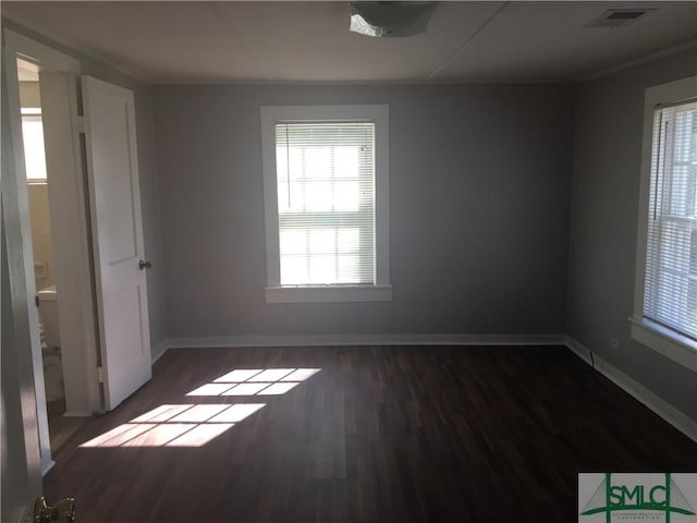 empty room with wood finished floors, baseboards, and visible vents