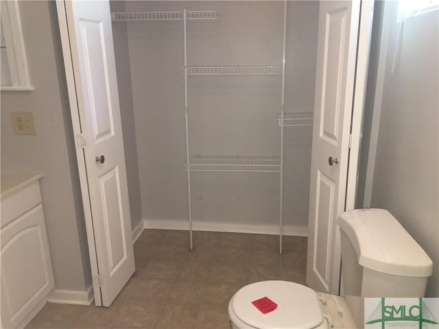 bathroom with tile patterned flooring, toilet, vanity, and baseboards