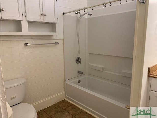 bathroom featuring tile patterned flooring, tub / shower combination, toilet, and tile walls