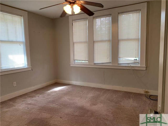 carpeted spare room featuring baseboards and a ceiling fan