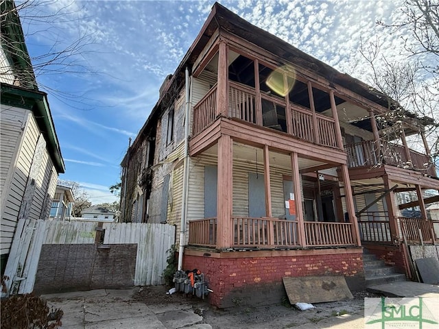 view of property exterior with a balcony, fence, and covered porch