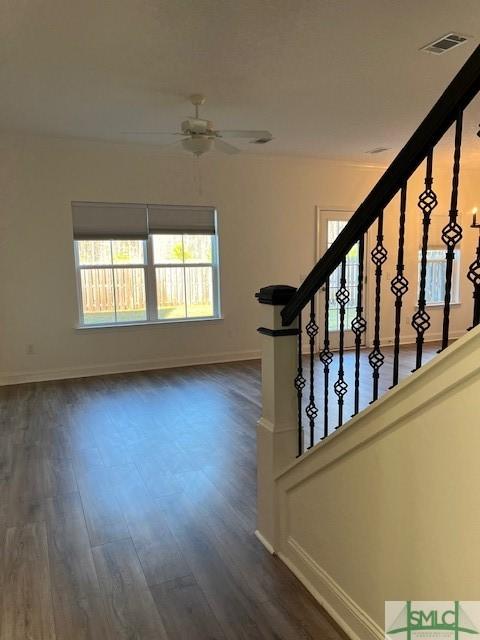 interior space with visible vents, baseboards, stairs, a ceiling fan, and dark wood-style flooring