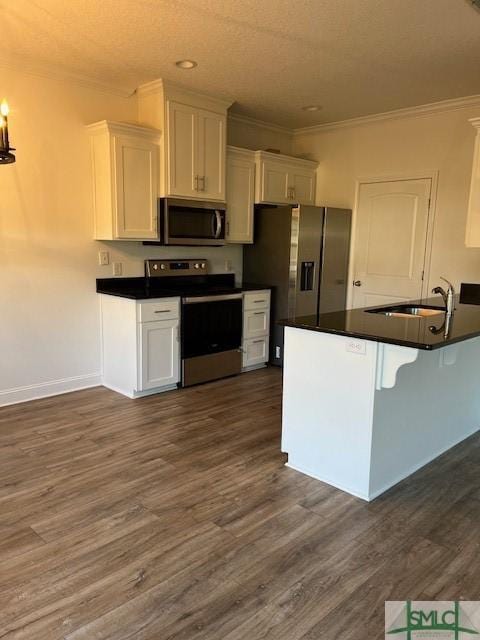 kitchen with dark countertops, appliances with stainless steel finishes, white cabinetry, and a sink