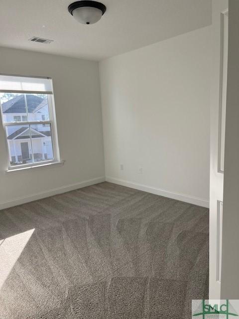 carpeted spare room with visible vents and baseboards