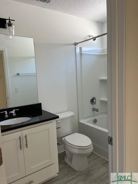 full bath with washtub / shower combination, a textured ceiling, vanity, and toilet