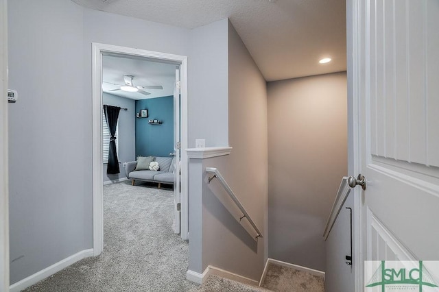 hall with an upstairs landing, baseboards, and carpet