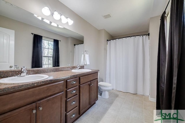 bathroom featuring double vanity, toilet, visible vents, and a sink