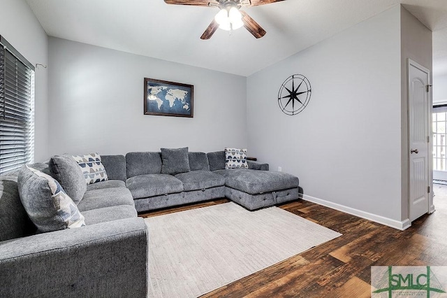 living room with ceiling fan, lofted ceiling, baseboards, and wood finished floors