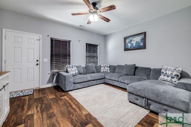 living area featuring dark wood finished floors, visible vents, baseboards, and ceiling fan