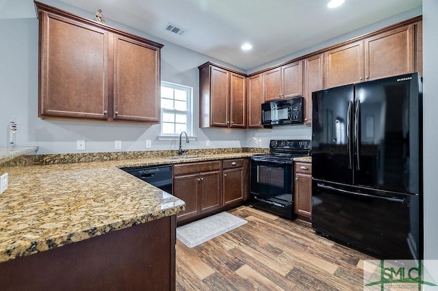 kitchen with wood finished floors, visible vents, recessed lighting, a sink, and black appliances