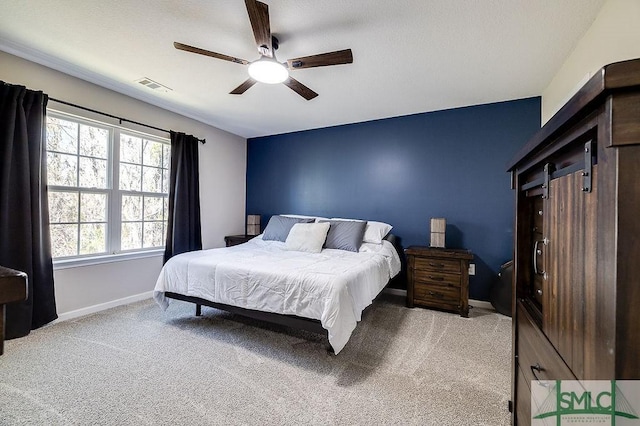 bedroom featuring light carpet, visible vents, a ceiling fan, and baseboards