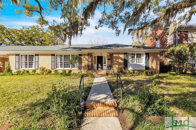 ranch-style home featuring brick siding, a front yard, and a gate