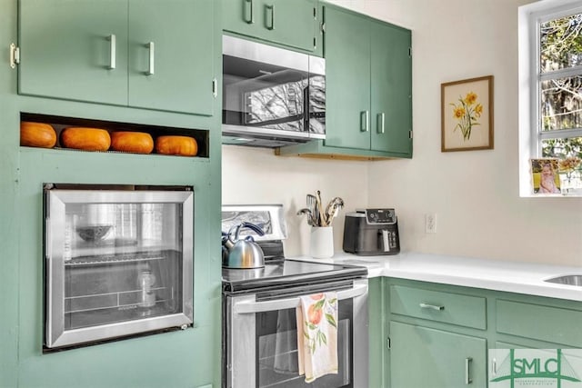 kitchen with light countertops, green cabinetry, and stainless steel appliances