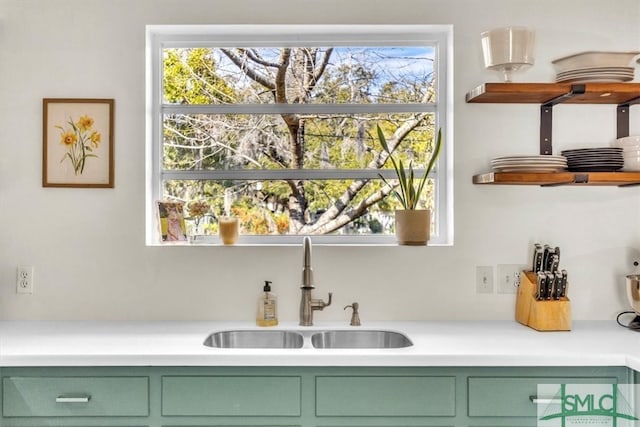 kitchen with a sink, light countertops, and green cabinetry