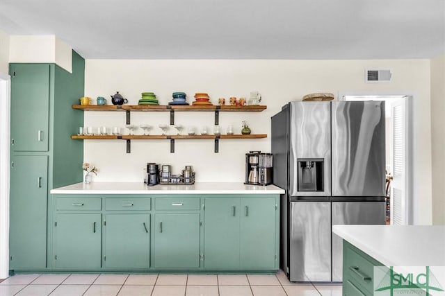 kitchen with open shelves, visible vents, stainless steel fridge, and light countertops