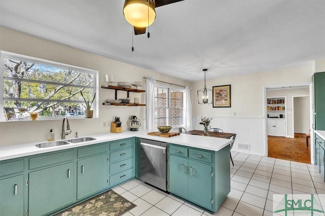 kitchen featuring stainless steel dishwasher, a peninsula, light countertops, and a sink