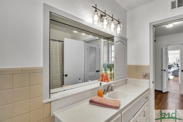 full bathroom with visible vents, vanity, tile walls, and wood finished floors