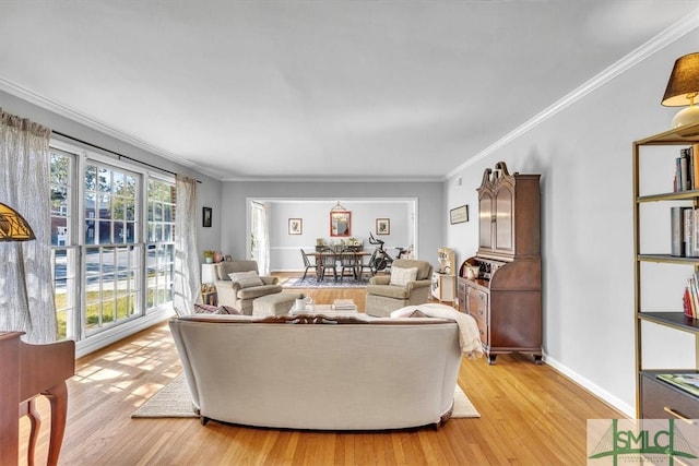 living area featuring crown molding, light wood-style floors, and baseboards