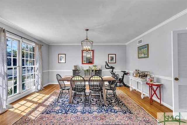 dining space with visible vents, crown molding, baseboards, wood finished floors, and a notable chandelier