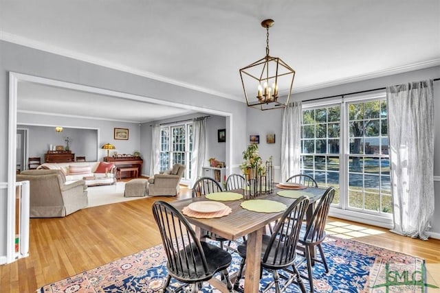 dining area with a chandelier, wood finished floors, and crown molding