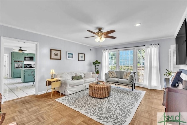 living area with baseboards, a ceiling fan, and ornamental molding