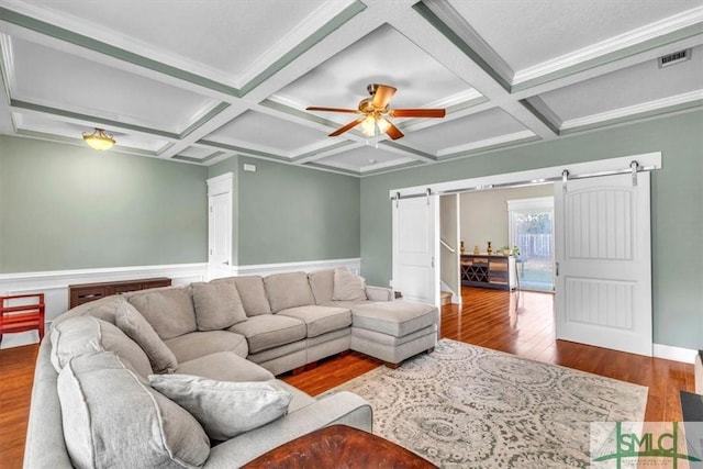 living room featuring visible vents, beamed ceiling, a barn door, wood finished floors, and coffered ceiling