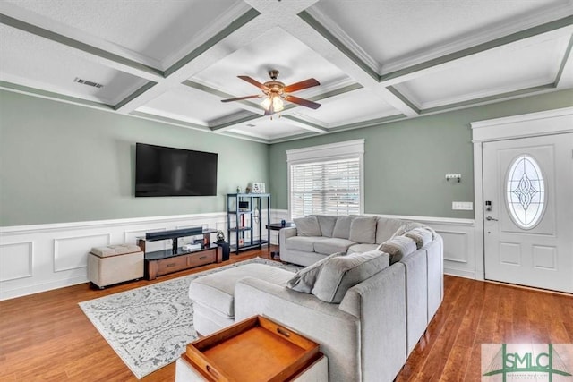 living room featuring visible vents, ceiling fan, beamed ceiling, wainscoting, and wood finished floors