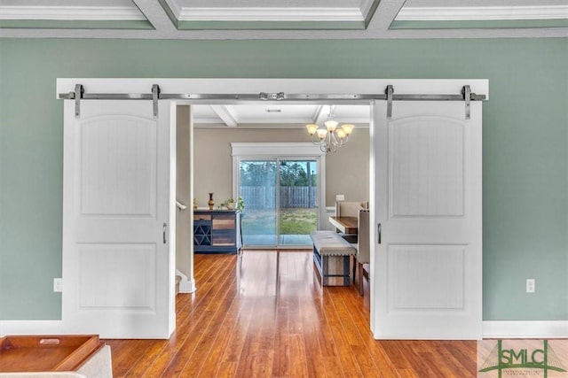 corridor with a barn door, beamed ceiling, and wood finished floors