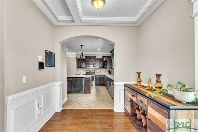 bar with wine cooler, light wood-style floors, appliances with stainless steel finishes, crown molding, and backsplash