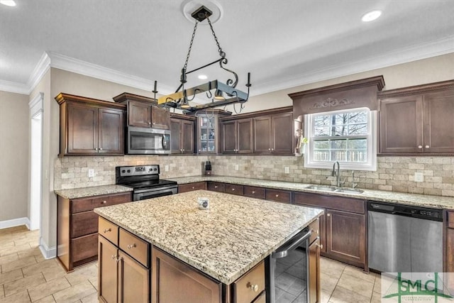 kitchen featuring beverage cooler, a kitchen island, a sink, appliances with stainless steel finishes, and crown molding