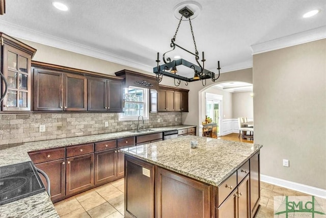 kitchen with light stone counters, arched walkways, a sink, stainless steel dishwasher, and a center island