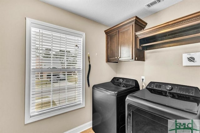 laundry room featuring baseboards, visible vents, cabinet space, a textured ceiling, and washer and clothes dryer