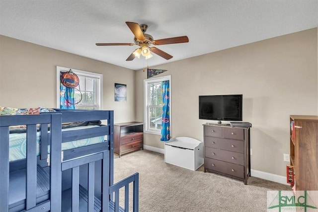 carpeted bedroom with ceiling fan, a textured ceiling, and baseboards