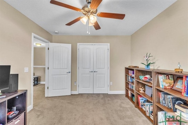 living area featuring ceiling fan, baseboards, and carpet