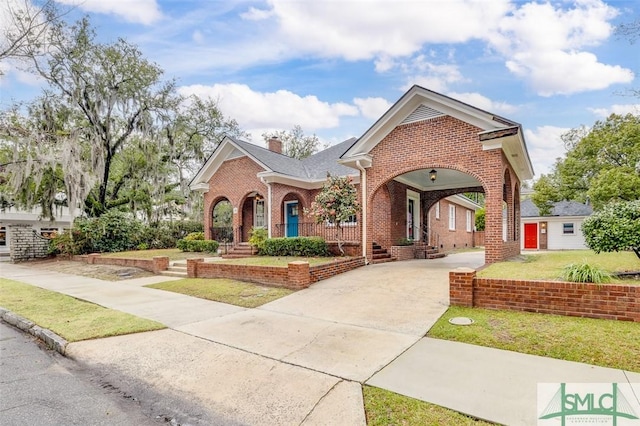 view of front facade featuring a front lawn, brick siding, driveway, and a chimney