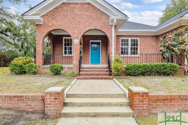 property entrance with brick siding, covered porch, and a shingled roof